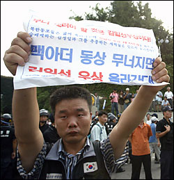 한 우익단체 회원이 '맥아더 동상 넘어지면 김일성 우상 올라간다'는 글이 적힌 종이를 들고 있다. 